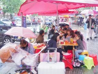 假期降雨，游客撑伞排队等美食