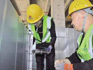 秦淮数据零碳数据中心项目施工现场，工人在安装室内通风管道。