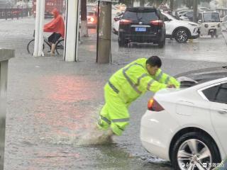 聊城暴雨中一幕，轿车积水中熄火，执勤交警赤脚推行……