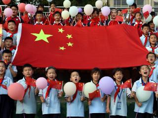 迎接国庆节，少年儿童围绕国旗祝福祖国