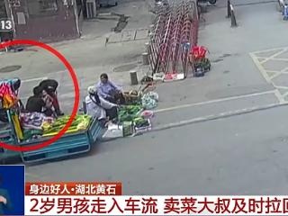 2岁男孩走入车流 卖菜大叔及时拉回