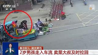 2岁男孩走入车流 卖菜大叔及时拉回